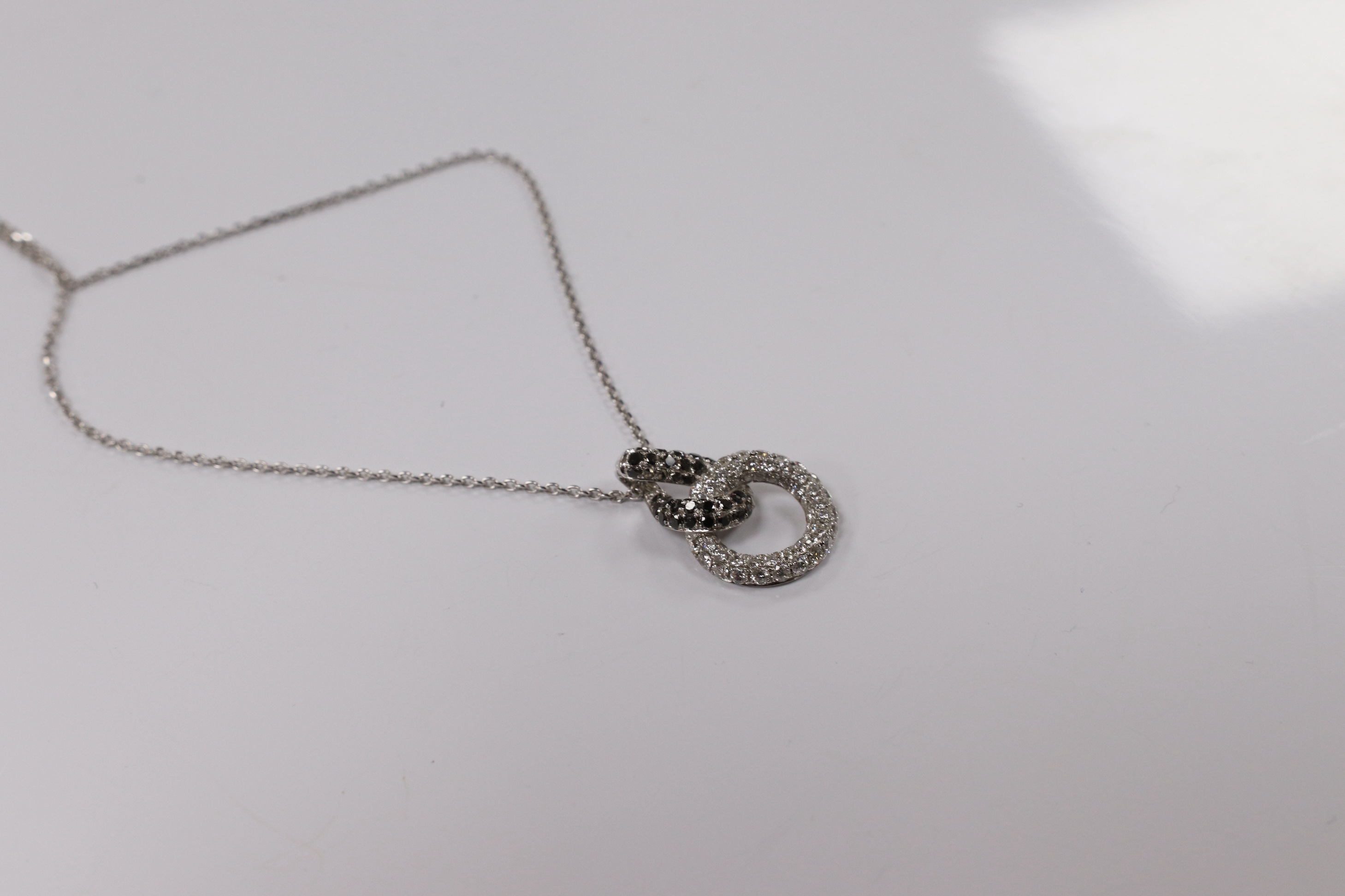 A modern 18k white metal and diamond chip set double loop pendant, 20mm, on an 18k white metal chain, 40cm, gross weight 4.1 grams. Condition - fair